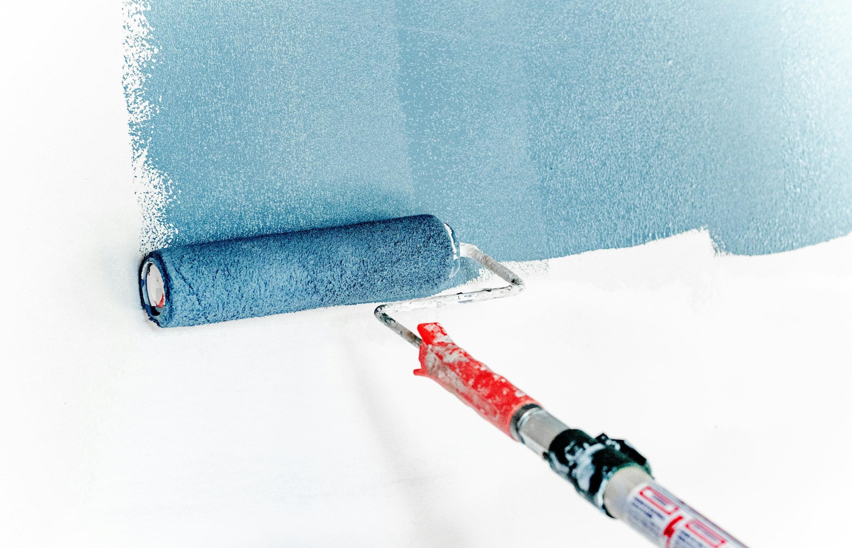 Paint roller applying blue paint to an interior wall