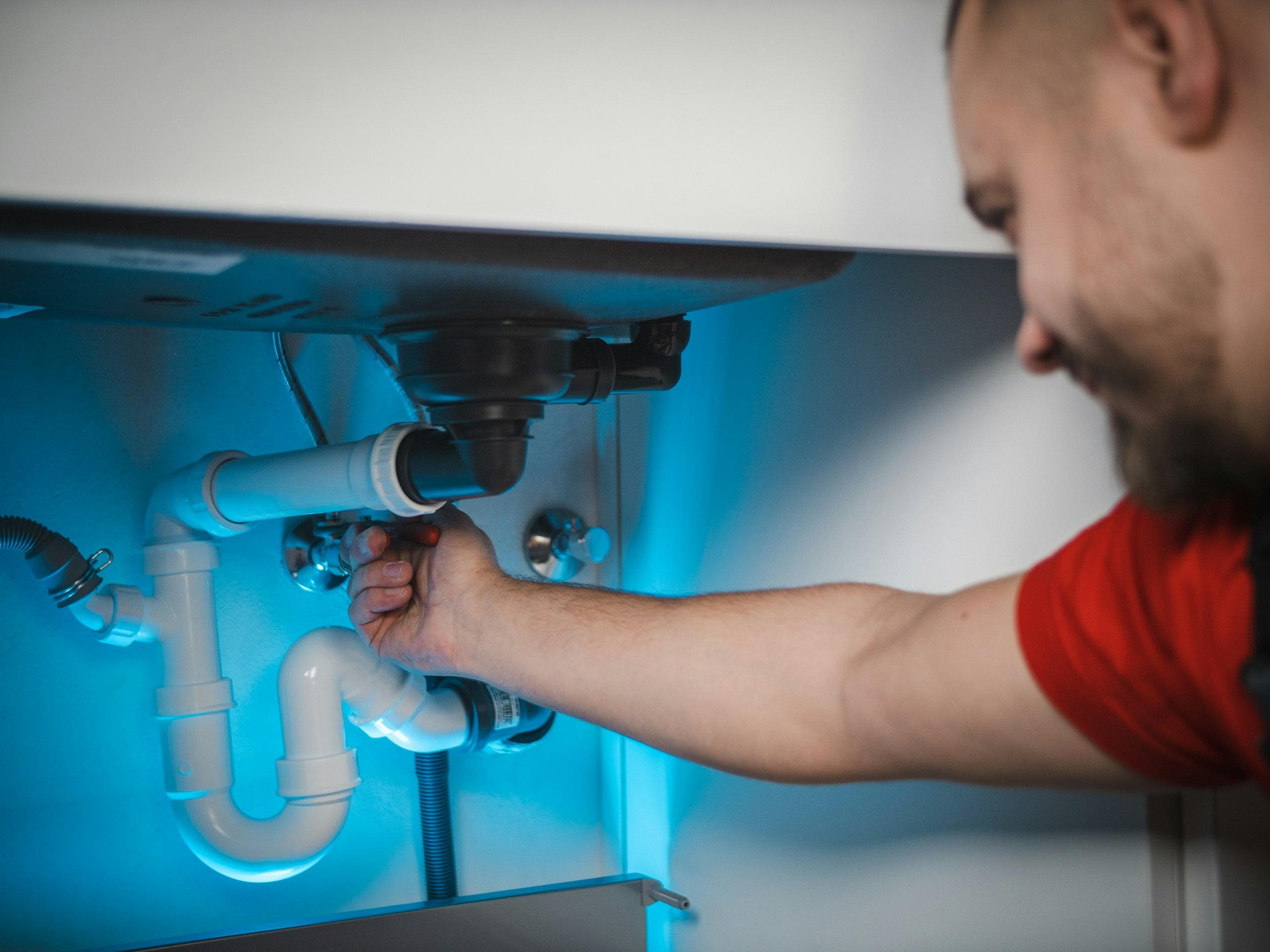 Plumber fitting a P-trap under a kitchen sink