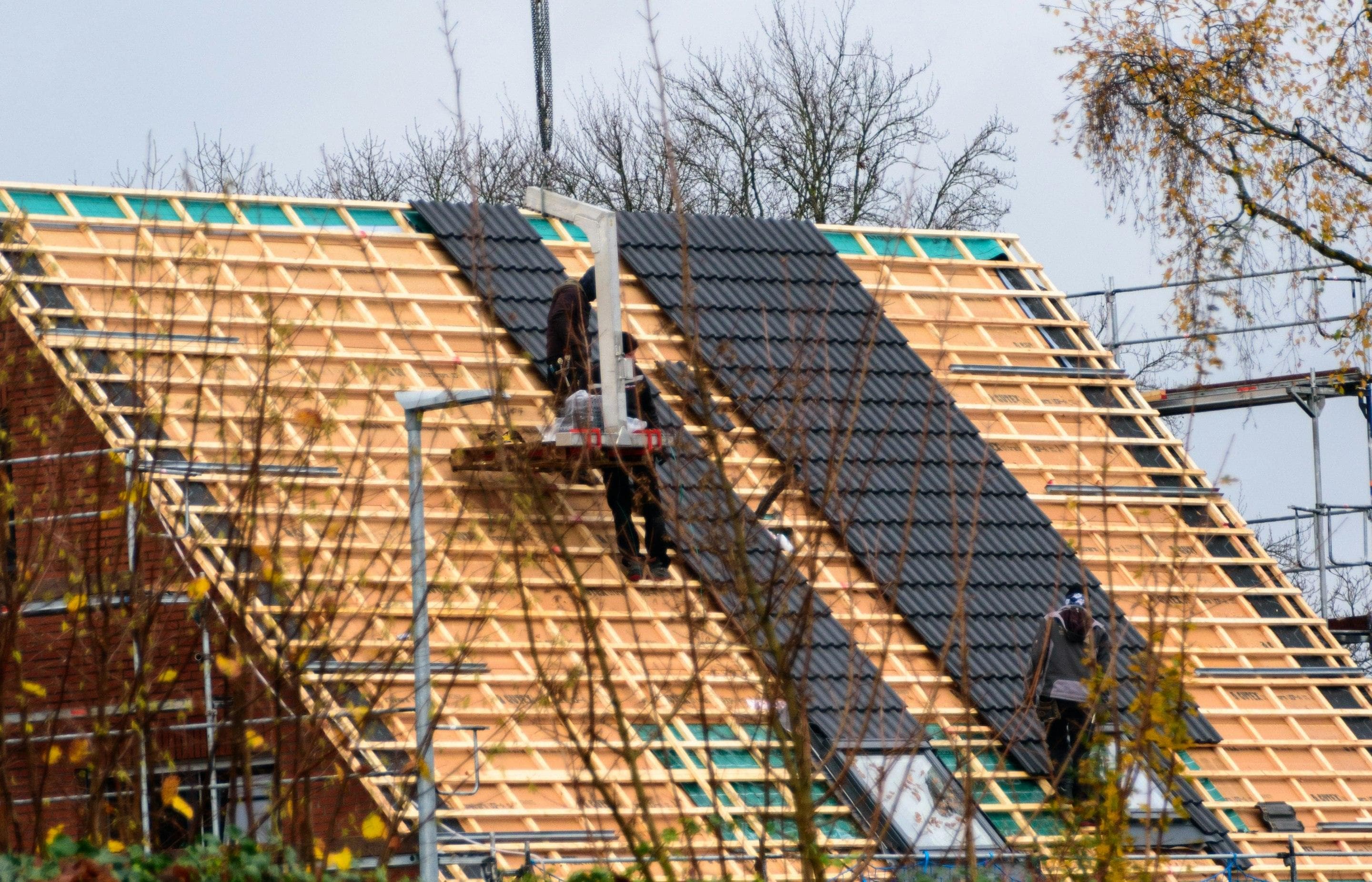 Roofers installing tiles on a house under construction